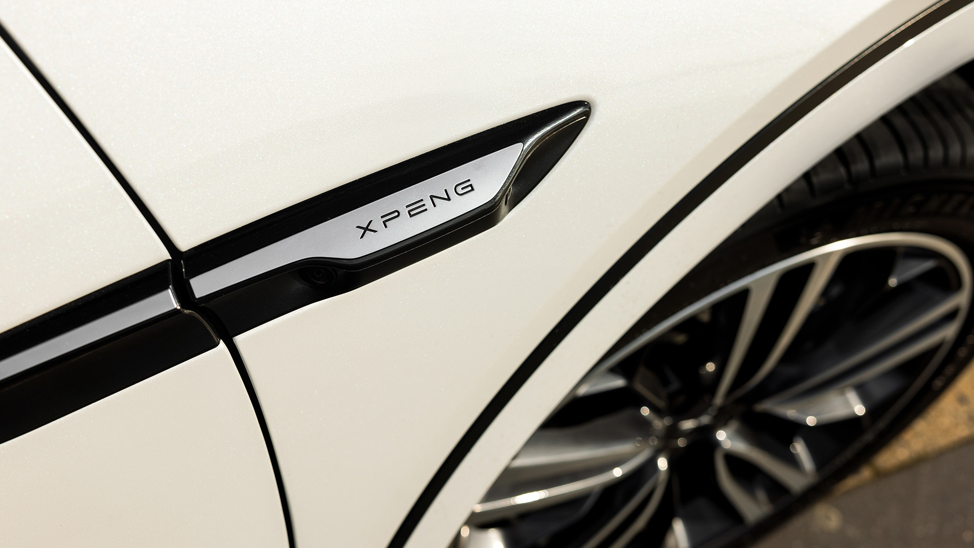 XPENG G6 front right panel logo up close with wheel in view.